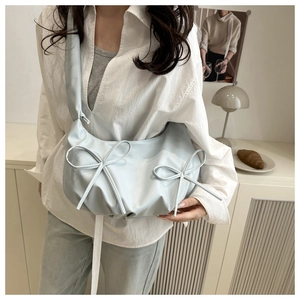 Close-up of light blue cloud bag featuring shiny pleated fabric and dual bow details
