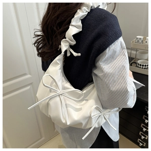 Close-up of a white cloud bag featuring soft faux leather and delicate bow accents