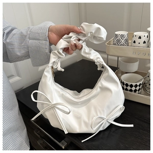Detail of white PU leather cloud bag featuring ruched handle and side bow decorations