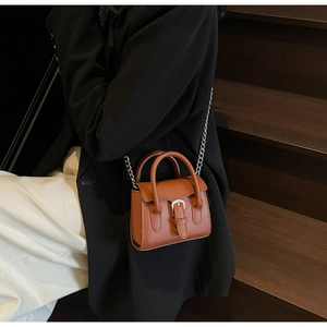 Schicke braune Mini-Umhängetasche mit Silberkette über einem klassischen schwarzen Blazer