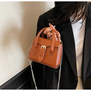 Detailaufnahme einer braunen Leder-Mini-Handtasche mit silberner Kette und Schnalle