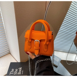 Detail der leuchtend orangefarbenen Mini-Handtasche mit silberner Kette und Schnalle