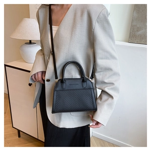 Detail of black contrast stitch handbag with leather texture and woven pattern detail