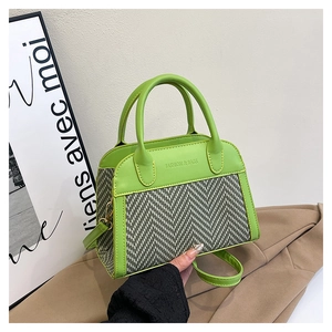 Detail of green leather and herringbone contrast handbag with embossed text