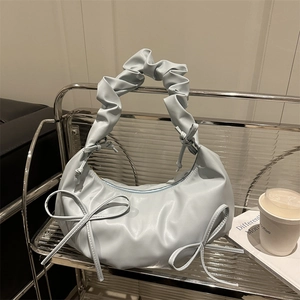 Light blue half-moon shoulder bag with pleated cloud handle and bow accents on a shelf