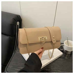 Detail of beige shoulder bag showing golden lock and chain strap in daily setting
