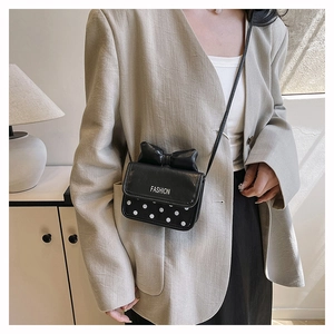 Détail d'un mini sac bandoulière noir avec des pois blancs et un nœud décoratif élégant
