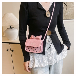 Mini sac bandoulière rose à pois noirs et grand nœud présenté dans un décor intérieur