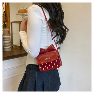 Détail du mini sac rouge à grand nœud et pois blancs sur cuir synthétique souple