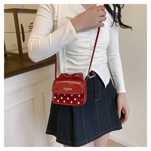 Détail d'un mini sac bandoulière rouge à pois blancs avec un nœud décoratif élégant