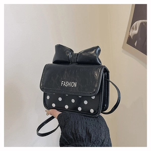 Close-up of mini square bag featuring black bow detail and white polka dot pattern