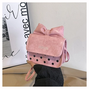 Détail d'un sac à bandoulière rose avec un grand nœud et des motifs à pois noirs