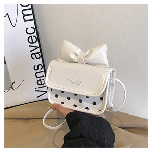Gros plan du mini sac blanc avec un grand nœud décoratif et un motif à pois noirs