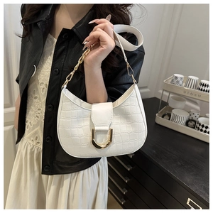 Detail van witte tas met krokodillenprint, gouden U-vormige gesp en metalen ketting