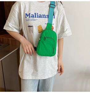 Green nylon chest bag with teal strap shown on a model for a stylish daily look