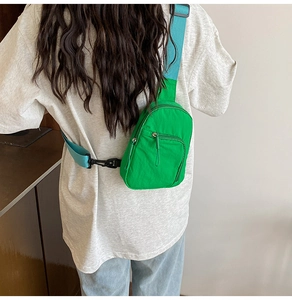 Detail of green nylon crossbody chest bag with blue strap on a model's back