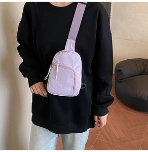 Close-up of light purple nylon chest bag with wrinkled texture and wide fabric strap