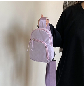 Detail view of light purple nylon chest bag showing zipper pocket and wide strap