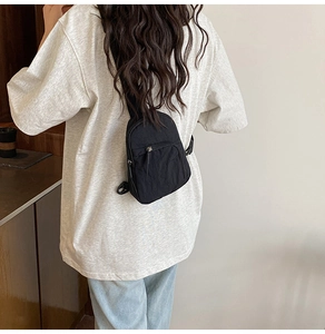 Detail view of a compact black nylon chest bag with adjustable strap and buckle closure