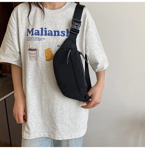 Detail view of durable black nylon crossbody bag with textured fabric and woven zipper puller