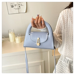 Detailed shot of a light blue trapezoid handbag with a signature gold metal lock buckle
