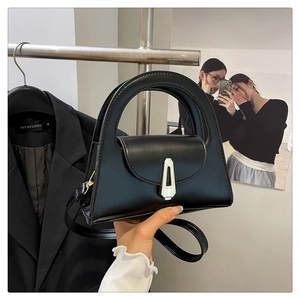 Close-up of black leather bag featuring silver metal buckle and semi-circle top handle