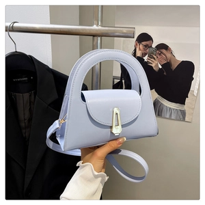 Detail of light blue semi-circular handbag featuring golden clasp and detachable strap