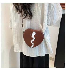 Détail du sac à bandoulière marron en forme de cœur avec motif de cœur brisé blanc