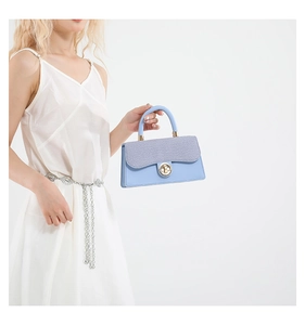 Detail of light blue handbag featuring a glitter flap texture and gold twist-lock closure