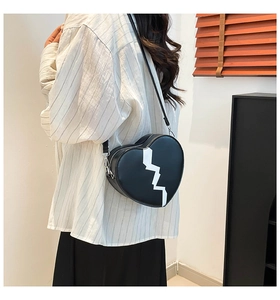 Detail of a heart-shaped crossbody bag with a white cracked pattern and metal zipper