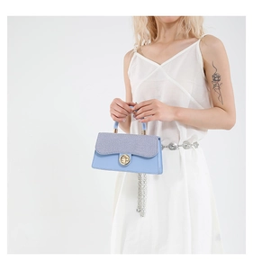 Detail of light blue textured handbag with grey woven flap and golden rotating metal lock