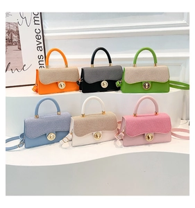 Detail view of colorful minimalist square handbags with gold clasp on white display stand