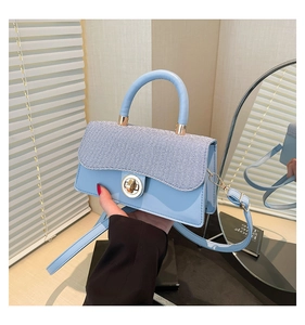 Detail of light blue crossbody bag featuring a golden twist lock and mixed fabric texture