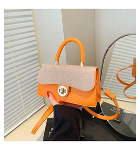 Detail of orange patchwork handbag with round metal clasp and smooth woven PU leather