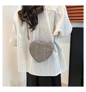 Detail of grey crocodile texture heart-shaped crossbody bag with silver chain accents