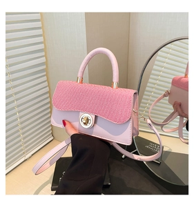 Detail of pink patchwork crossbody bag featuring a golden round twist lock and smooth texture