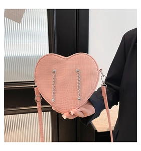 Detail of pink heart-shaped bag with crocodile texture and decorative silver chains