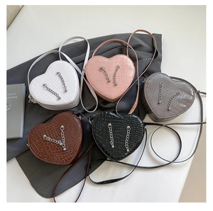 Macro detail of heart-shaped crossbody bags featuring crocodile texture and silver chains