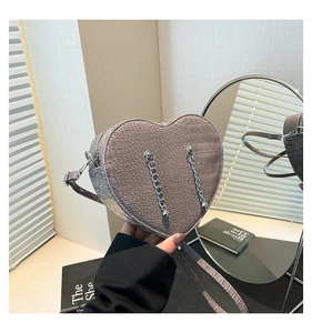 Macro shot of heart-shaped crossbody bag featuring crocodile texture and silver chains