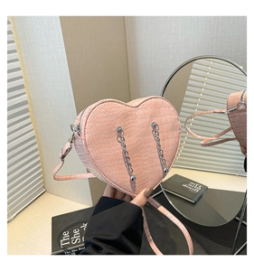 Detailed view of pink heart-shaped bag with crocodile texture and silver chain fringe