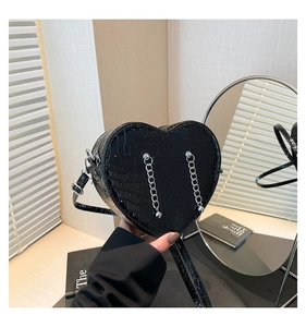 Detail of black heart-shaped handbag with crocodile texture and silver chain strap