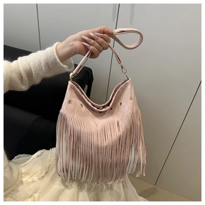 Detail of light pink crossbody bag featuring decorative long fringes and gold metal studs