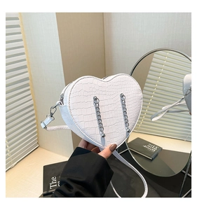 Detail of white heart-shaped crossbody bag with crocodile texture and silver chain