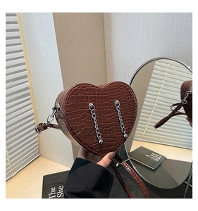 Detailed macro view of heart-shaped dark brown crossbody bag with crocodile texture