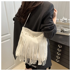 Detailed view of white oversized tassel shoulder bag with golden metallic eyelets