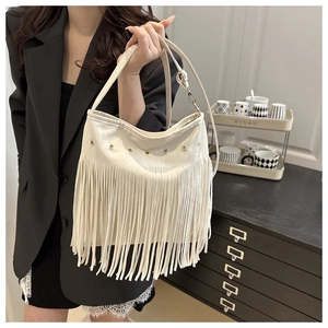Detail shot of a white tassel shoulder bag with golden metal eyelets and textured faux leather