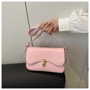 Detail of pink faux leather crossbody bag featuring a golden oval twist lock closure