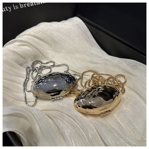 Detail of gold and silver shell-shaped mini bags with wavy textures and snake chains
