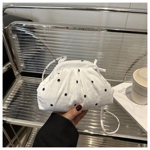 Close-up of white cloud-shaped mini bag with elegant black floral embroidery and crinkled texture