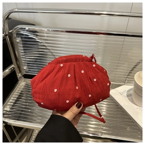 Detail of red floral drawstring pouch with pleated fabric texture and thin strap